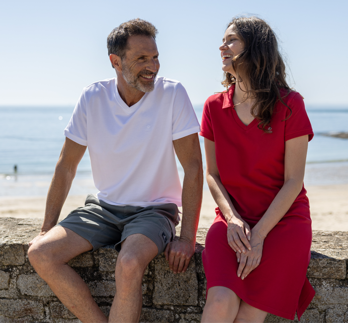 Homme et femme assis en bord de mer portant des vêtements en coton bio