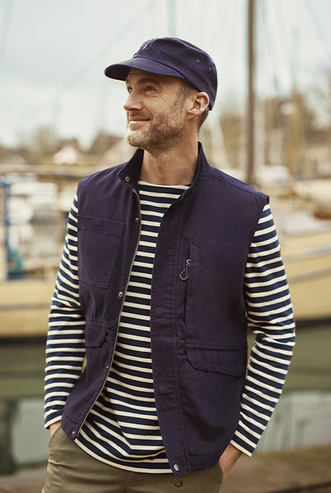 homme portant une marinière bleu marine et blanche avec une veste sans manche