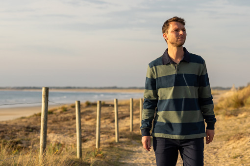 Un homme qui marche et porte un polo rugby sur un sentier côtier